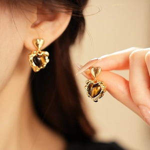 Macro detail of gold plated heart earrings featuring natural tiger eye stone inlay