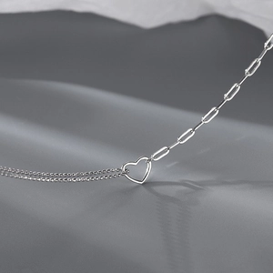 Macro shot of silver clavicle necklace with heart pendant and mixed link chain