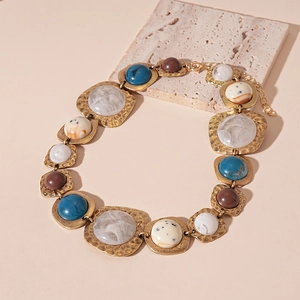 Detail of vintage geometric resin charms on a gold chain necklace for women