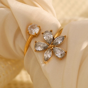 Gros plan sur la bague fleur dorée 18K ornée de zircons sur un tissu en soie douce