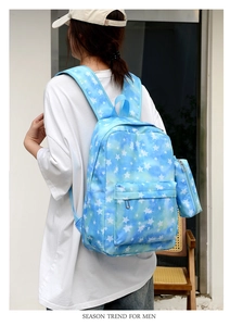 Blue backpack with white star pattern and matching small pouch on a street model