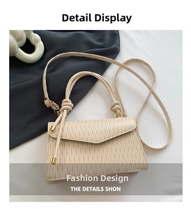 Detail view of cream shoulder bag with vertical pleated texture and knotted handle strap