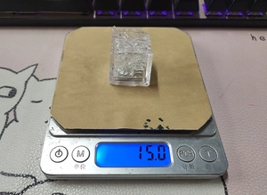 Macro shot of a glowing ice cube shaped LED light being weighed on a digital scale