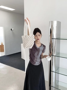 White handwoven bucket bag featuring intricate cutout mesh design shown with modern styling