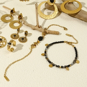 Detail of gold-plated stainless steel jewelry set featuring black stones and floral motifs
