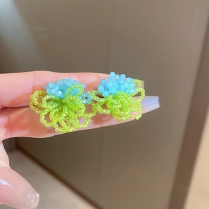 Détail de boucles d'oreilles fleuries faites main en perles bleu clair et vertes