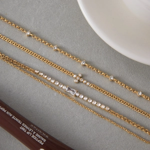 Gros plan de quatre bracelets dorés avec zircons, pendentifs en croix et cristaux
