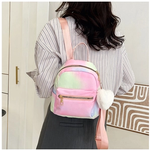 Back view of a mini gradient backpack with a white heart plush keychain on a female model