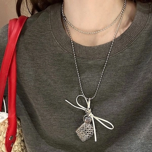 Detail of silver double-layered beaded necklace with bow and grid square pendant