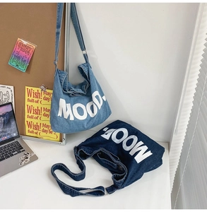 Detail of light and dark blue denim messenger bags with white MOOD. text print