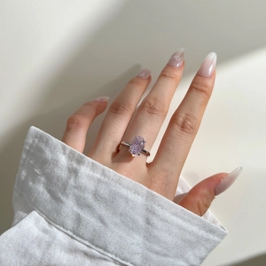 Detailed view of pink oval-cut gemstone ring on hand with elegant four-prong setting