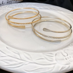 Detail of gold and silver multi-layer spiral open bracelets with hammered texture on a plate