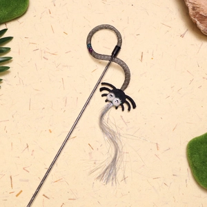 Detail of a spider cat wand toy featuring silver silk tassels and a glittery eye design