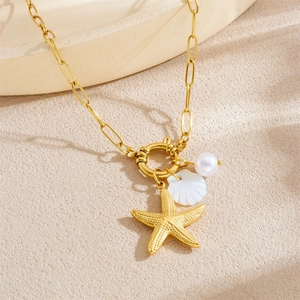 Gold ocean themed necklace with starfish shell and pearl pendants on a textured surface