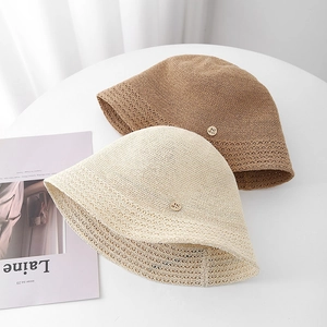 Détail de chapeaux cloches tissés avec motifs ajourés et boucles dorées sur une table