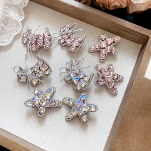Macro shot of sparkling crystal studded dog and star hair clips on a vintage wooden tray