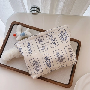 Detail of floral printed makeup bag with simple wish label on wooden tray