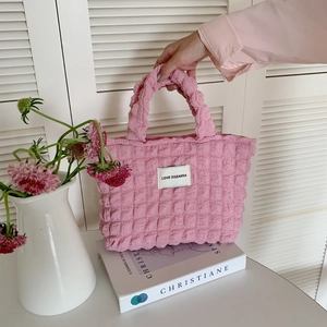 Detailed view of pink bubble texture tote bag with LOVE SOZAKKA woven label on top of books