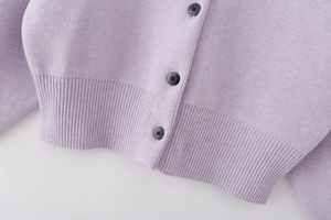 Close-up of lilac knit cardigan hem featuring ribbed cuffs and three black buttons