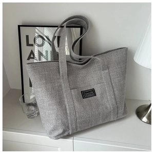 Minimalist grey canvas tote bag with front pocket shown in a modern Nordic interior setting
