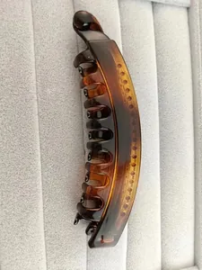 Detail view of large tortoiseshell banana clip with inner teeth on grey velvet display