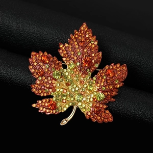 Macro detail of high-end maple leaf brooch with vibrant gradient rhinestones and crystals