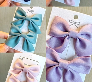 Detail of colorful bow hair clips on cards featuring pastel satin ribbon textures