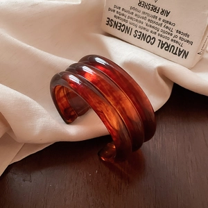 Macro detail of triple-ridged amber resin cuff bracelet on rustic wooden surface