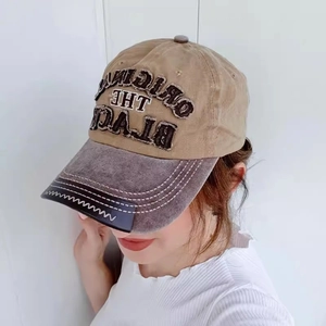 Detail of embroidered khaki baseball cap with distressed brim worn by a model outdoors