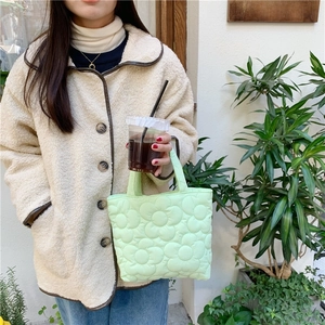 Detail of light green quilted tote bag featuring 3D floral embroidery and satin finish