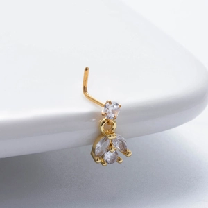 Macro shot of gold nose stud with sparkling zircon pendant on white curved surface