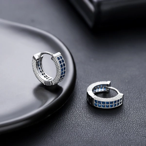 Vue macro de boucles d'oreilles argentées serties de zircons bleus sur plusieurs rangs