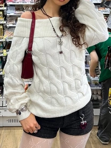Close-up of white off-shoulder knit sweater showing chunky texture and long sleeves
