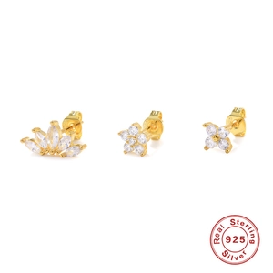 Macro view of three gold 925 sterling silver stud earrings with floral and clover designs