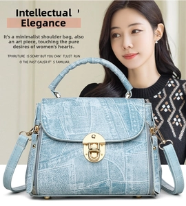 Close-up of light blue denim texture handbag with gold shield turn-lock on knit sweater