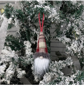 Close-up of a festive red plaid Christmas gnome hanging on a snowy Christmas tree