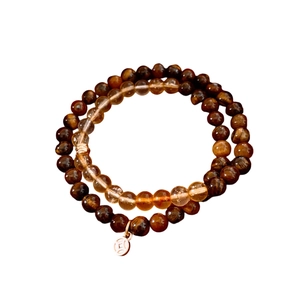 Bracciale di perle occhio di tigre e vetro con ciondolo a moneta d'oro su sfondo bianco