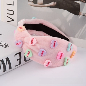 Close-up of pink plush headband featuring colorful heart charms with XOXO and LOVE text