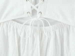 Detailed macro view of white cotton lace dress featuring lace-up back and ruched waist