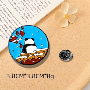 Detail of round panda enamel pin with blue snowy scene and floral accents, 3.8cm diameter