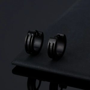 Polished black stainless steel hoop earrings for men and women on a reflective surface