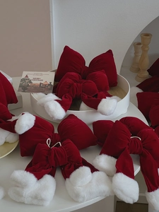 Detail of red velvet Christmas bows with white faux fur trim on a cozy table setting