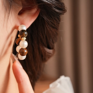 Primer plano detallado de pendientes en forma de C con perlas de ojo de tigre en una modelo