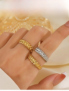 Close-up of three stacked twisted chain rings in gold and silver finish on a hand