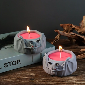 Gothic bat candle holders with red eyes and pink wax on a vintage wood surface