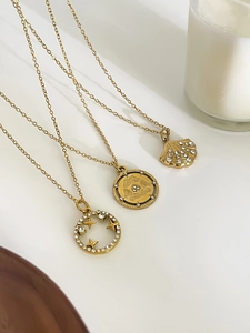 Three gold necklaces featuring shell, star, and butterfly pendants with crystal inlay