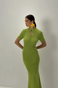 Dettaglio dell'abito in maglia verde con scollo a goccia, fiocco e trama a costine
