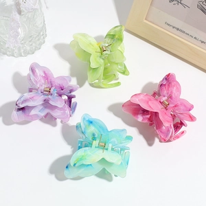Detail of four butterfly hair claws with colorful marble gradient textures on white surface