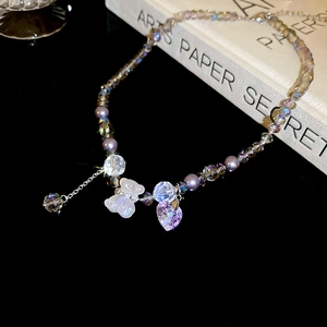 Macro detail of purple crystal bear necklace with butterfly heart charms on beads