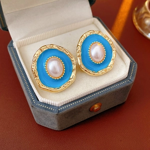 Detail of vintage golden earring with sky blue enamel and white oval pearl inlay